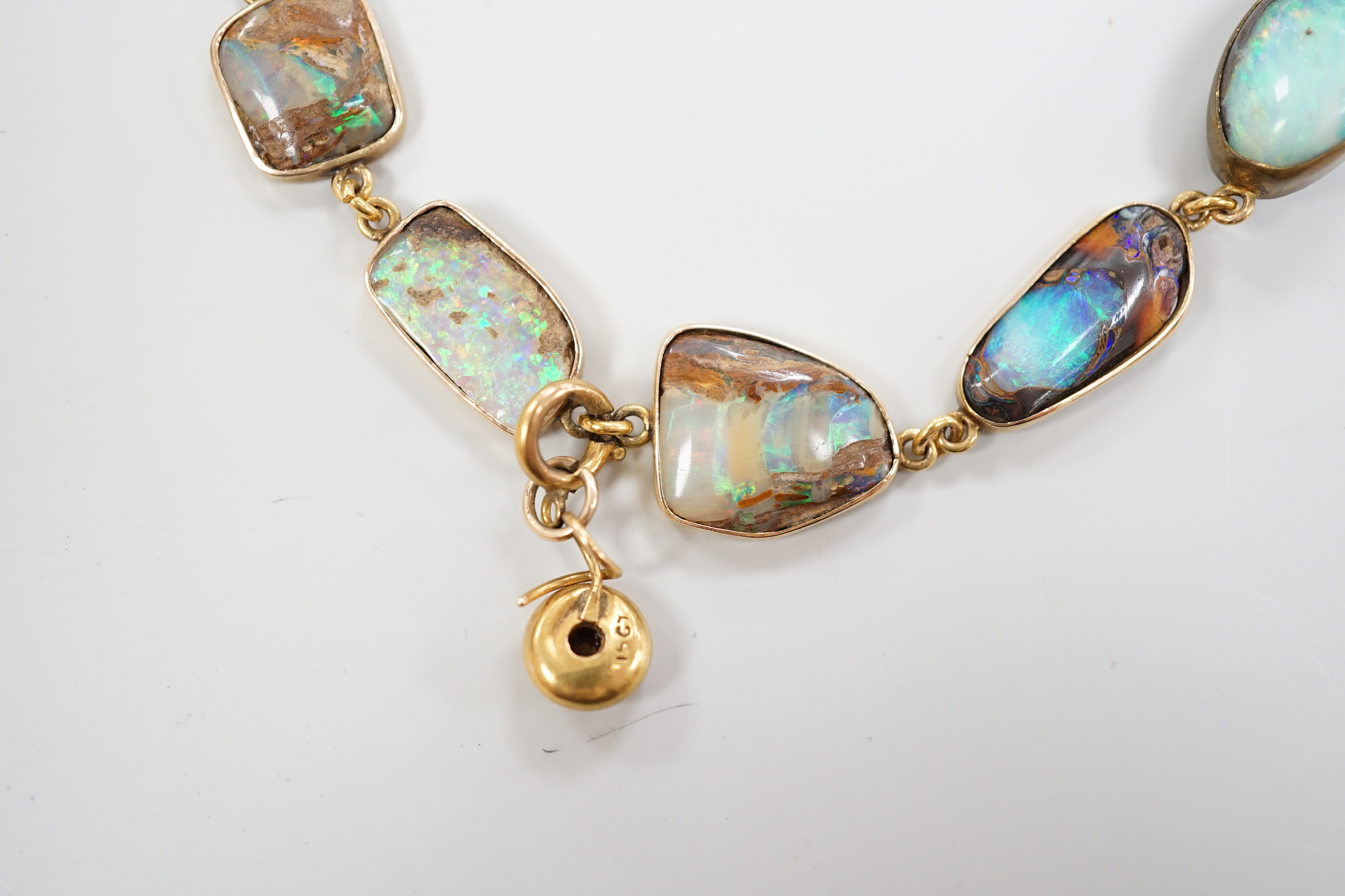 An early 20th century yellow metal and opal set bracelet, of various shapes and hung with central 15ct and diamond chip set charm, 21cm, gross weight 15 grams.